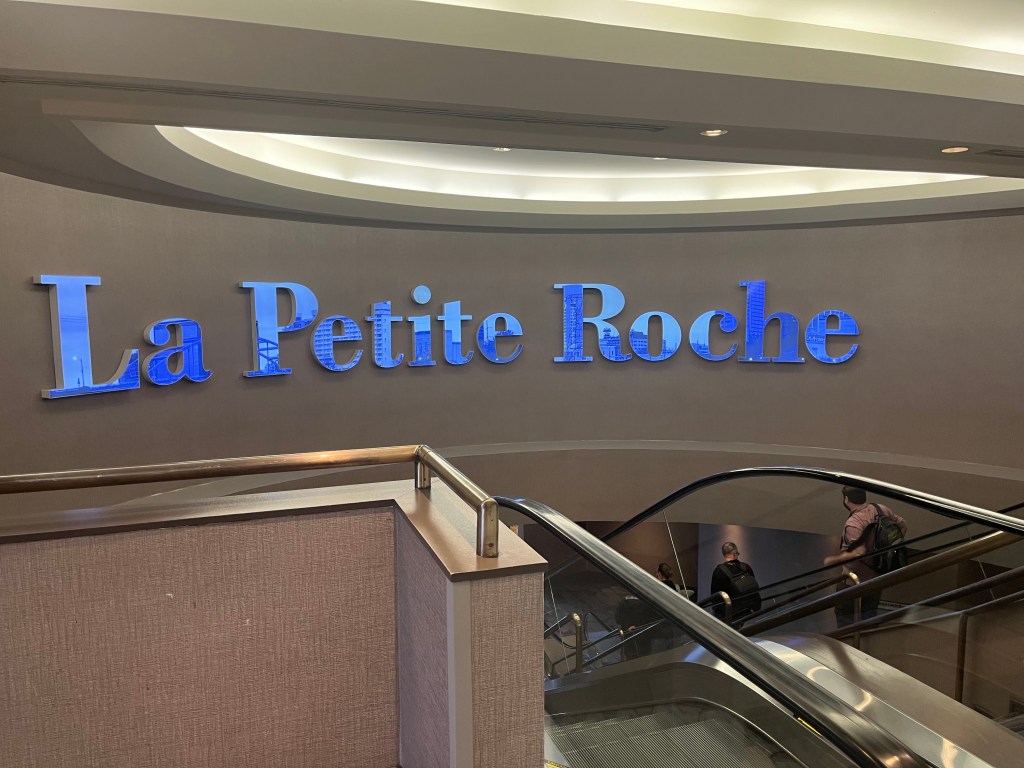 Huge blue sign over an escalator: "La Petite Roche"