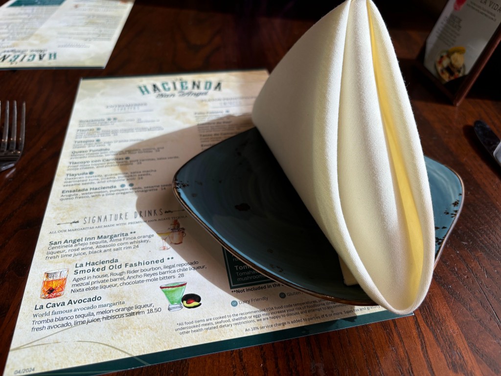 A napkin folded on a plate over a menu of Hacienda, a Mexican restaurant in Epcot