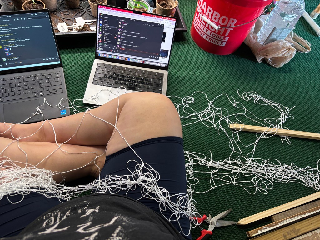 Me, sitting on a green mat, tangled in a nightmare of trellis string