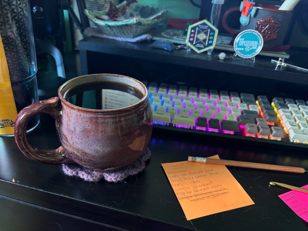 A mug of coffee in front of a rainbow keyboard