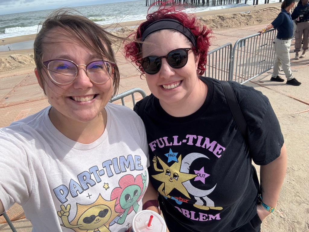 the author and her friend Nat, who has red hair and sunglasses, at the fall out boy concert, standing in front of the ocean. Their shirts read out the lyrics of "Hold Me Like a Grudge" - "Part Time Soul Mate Full Time Problem"
