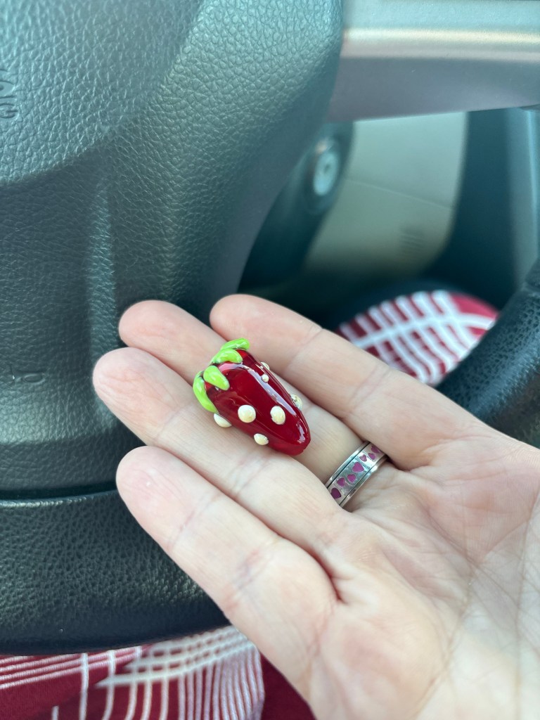A glass bead shaped like a strawberry.