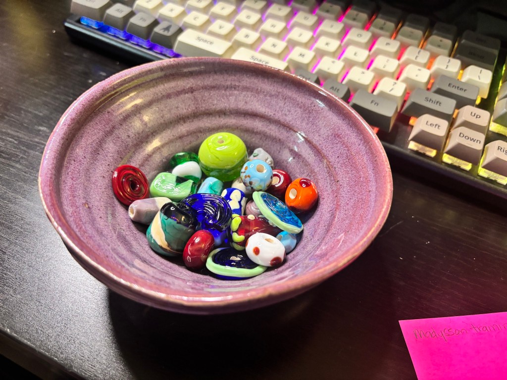A bowl full of colorful glass beads, made by the author. They are all unique and shiny.